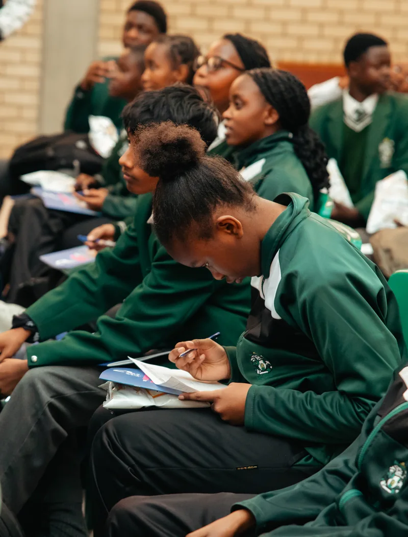 A learner writing in a notebook during EduCate at Midrand High School.