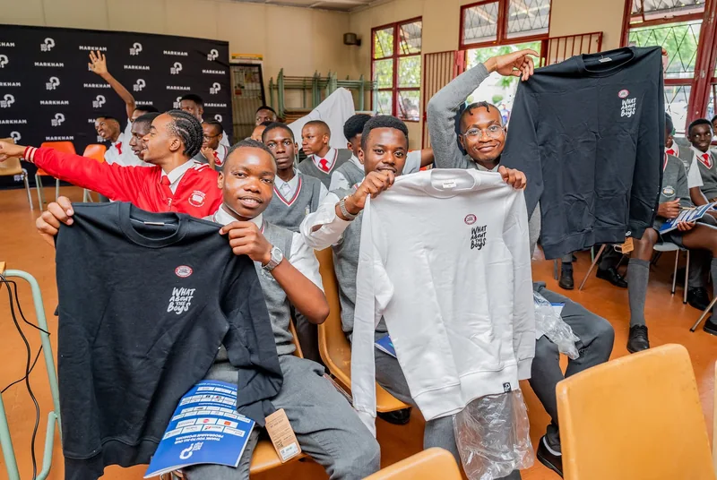 Learners holding up What About The Boys branded clothing during a programme gathering with Markham.