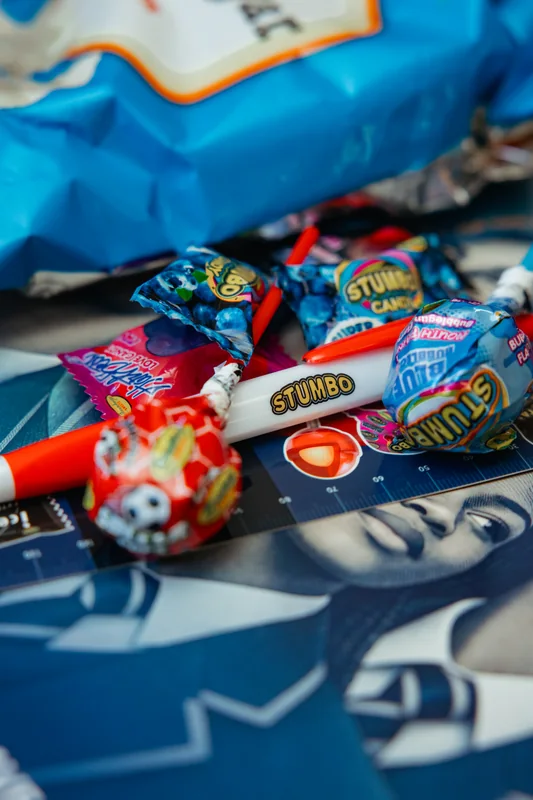 Sweets and red-and-white pens arranged on blue Rethink Rands programme materials.