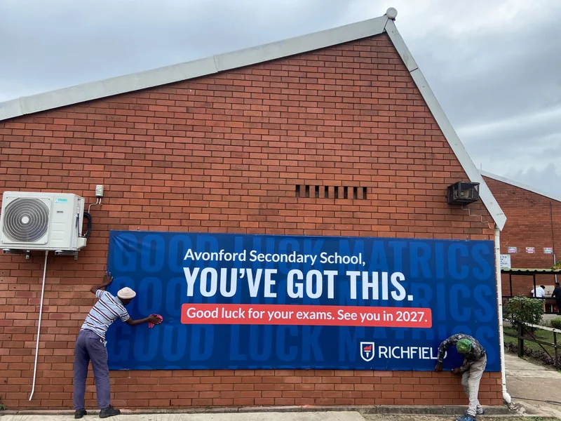 Installers mounting the Richfield billboard at Avonford Secondary School.