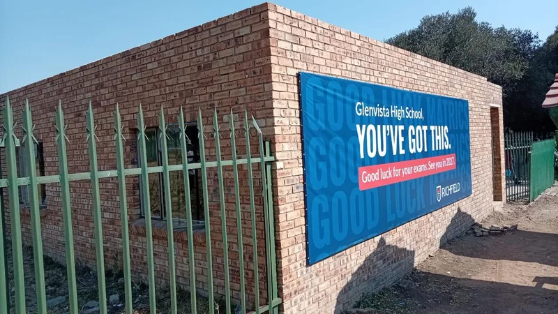 Blue Richfield billboard on a brick school building beside the fence at Glenvista High School.