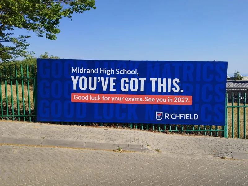 Blue Richfield exam encouragement billboard on the fence at Midrand High School.